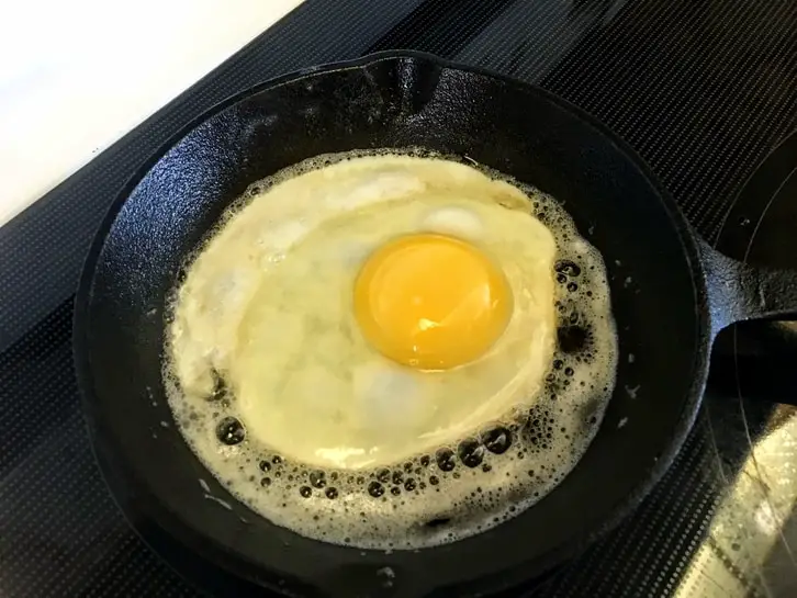 frying an egg in a small cast iron pan