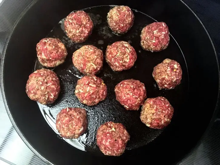 cast iron skillet full of homemade meatballs