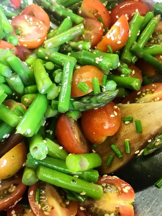 mixing asparagus and cherry tomato salad