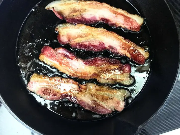 pasture-raised bacon sizzling in cast iron