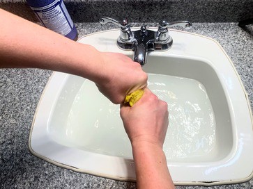 wringing a wash cloth over a bathroom sink